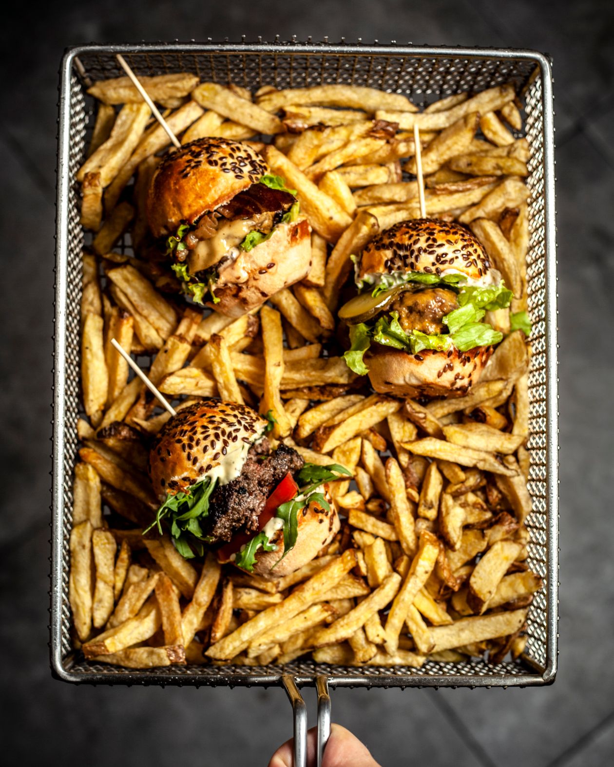 Burgers garnis et frites dorées, vus de dessus dans un panier à partager